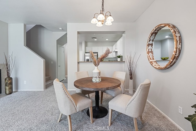 dining space featuring a notable chandelier and carpet flooring