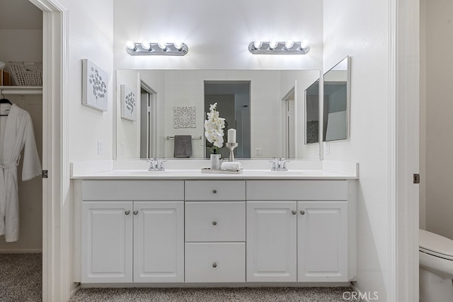 bathroom featuring dual vanity and toilet