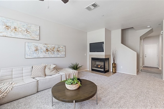 living room with light colored carpet, a tile fireplace, and ceiling fan