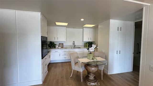 kitchen featuring hardwood / wood-style flooring, sink, and white cabinets