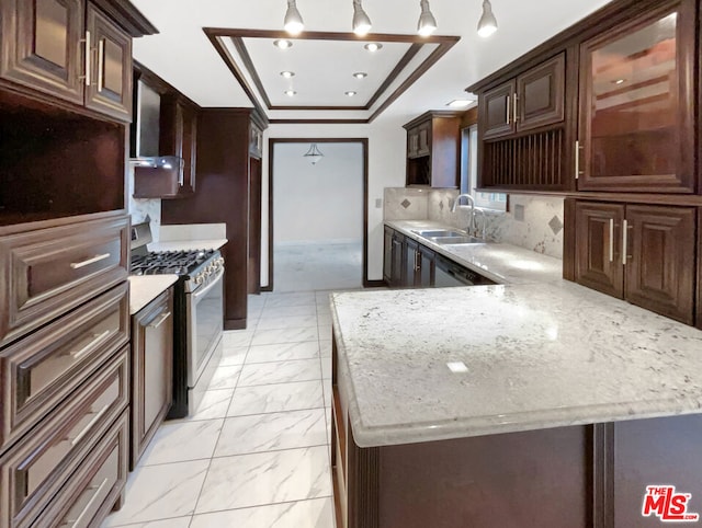 kitchen with decorative backsplash, light stone countertops, dark brown cabinets, sink, and stainless steel gas stove