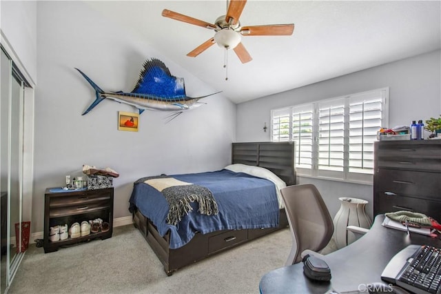 carpeted bedroom with ceiling fan, a closet, and vaulted ceiling