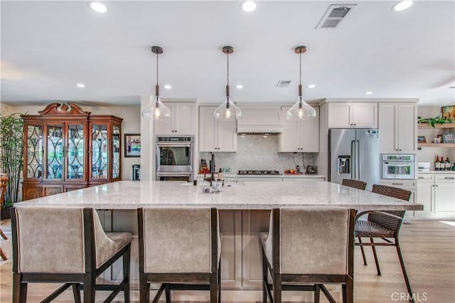 kitchen with a spacious island, white cabinets, and stainless steel appliances