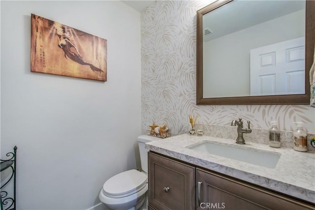 bathroom with vanity, toilet, and backsplash