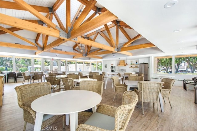 dining room with beam ceiling, high vaulted ceiling, and light wood-type flooring