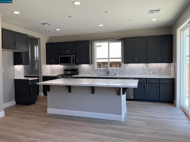 kitchen with a kitchen island, sink, stainless steel appliances, and tasteful backsplash