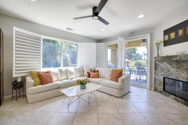 living room with a high end fireplace, a wealth of natural light, ceiling fan, and light tile patterned flooring