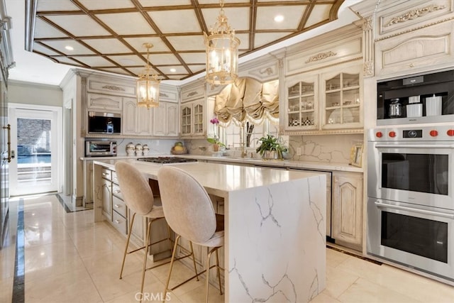 kitchen featuring coffered ceiling, hanging light fixtures, a kitchen island, decorative backsplash, and crown molding