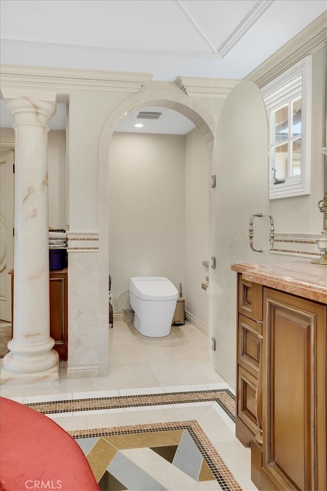 bathroom featuring vanity, tile patterned flooring, ornamental molding, decorative columns, and toilet