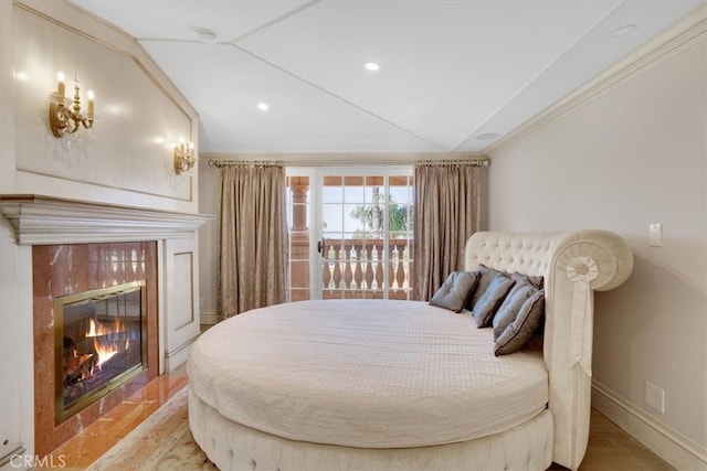 bedroom featuring a tile fireplace, ornamental molding, and light hardwood / wood-style flooring