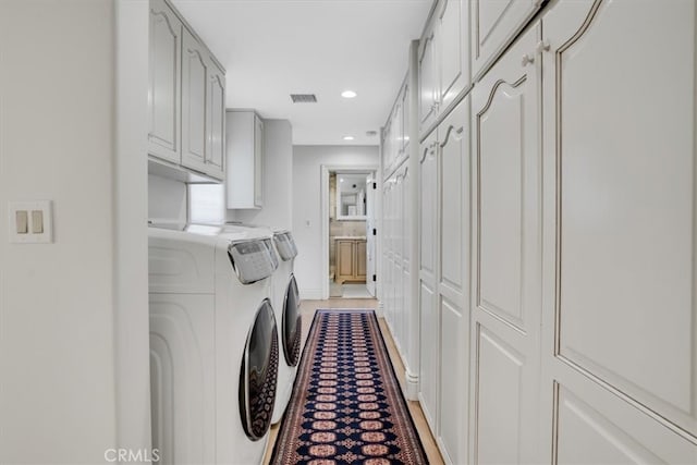 clothes washing area with separate washer and dryer and cabinets