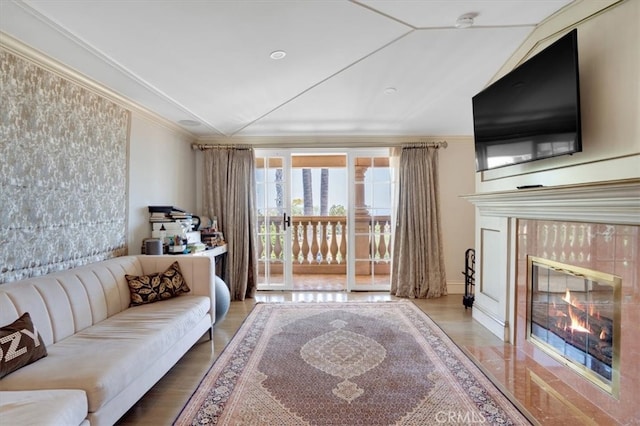 living room with wood-type flooring, crown molding, and a tile fireplace