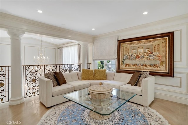 living room featuring a chandelier, decorative columns, light hardwood / wood-style floors, and crown molding