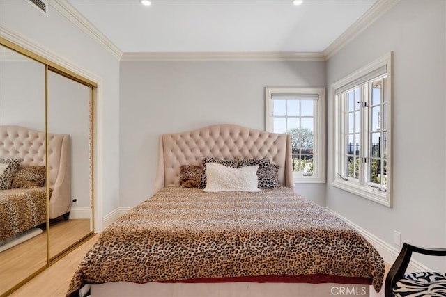 bedroom with wood-type flooring, ornamental molding, and a closet