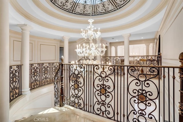 interior space with a tray ceiling, an inviting chandelier, and ornate columns