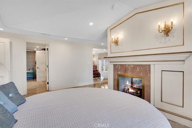 bedroom featuring light hardwood / wood-style floors, a fireplace, ornamental molding, and lofted ceiling