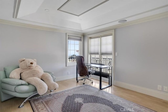 office area featuring attic access, baseboards, wood finished floors, and a tray ceiling