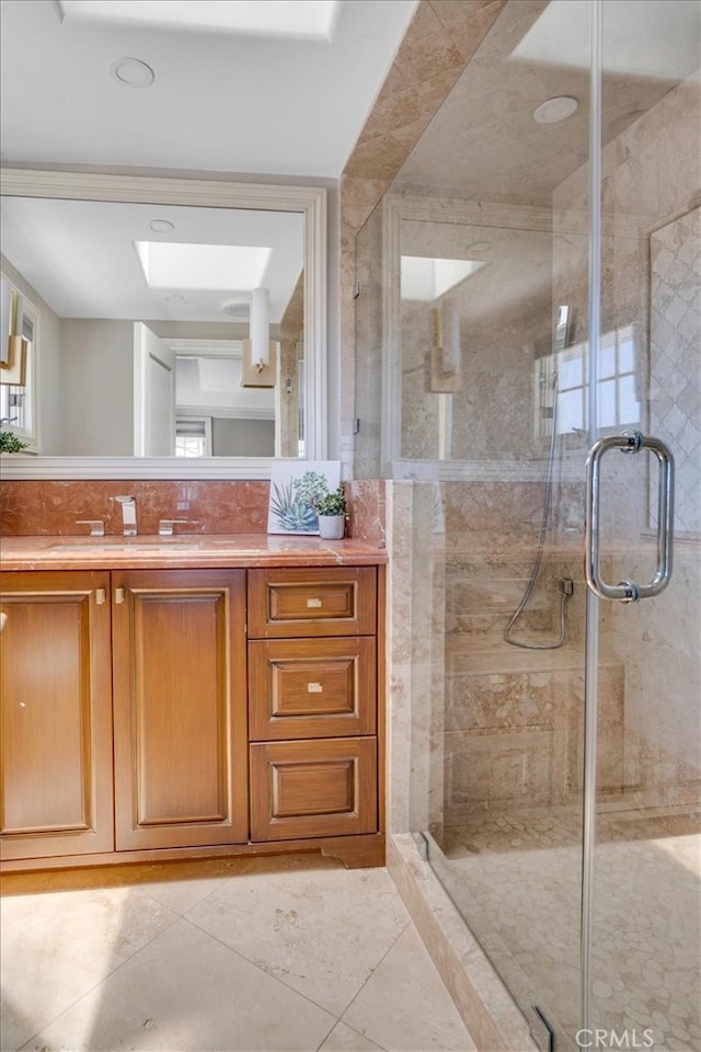 bathroom featuring walk in shower, tile patterned flooring, vanity, and a skylight