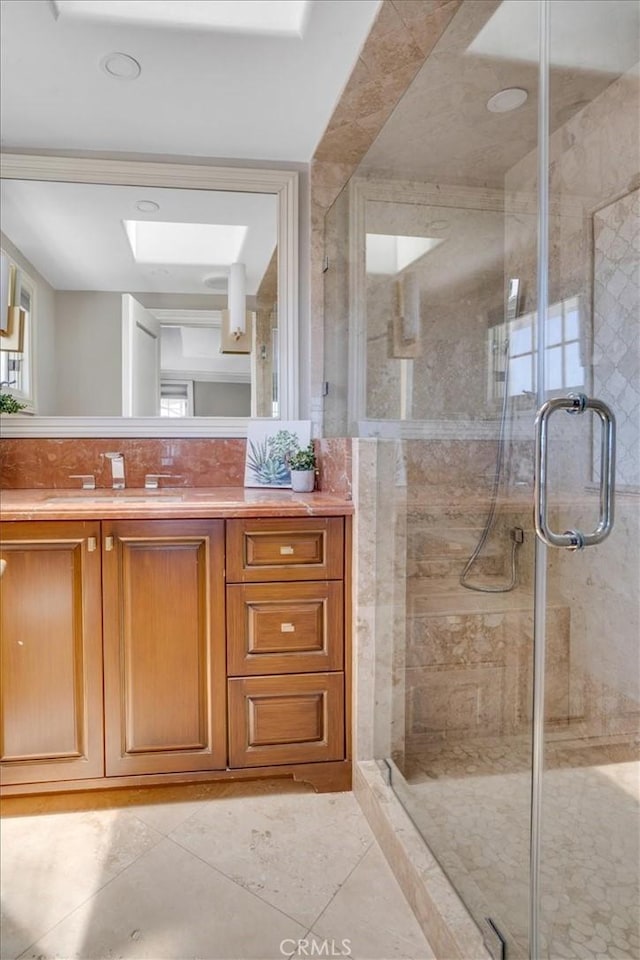 bathroom with a stall shower, a skylight, and vanity