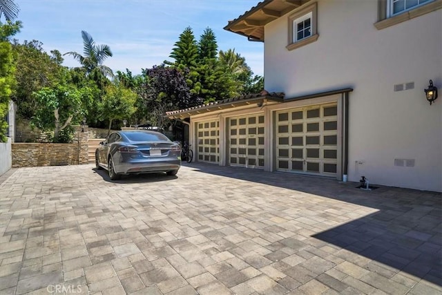 exterior space with stucco siding, decorative driveway, and a garage