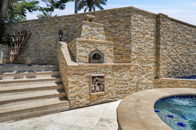 view of patio with an outdoor stone fireplace and fence