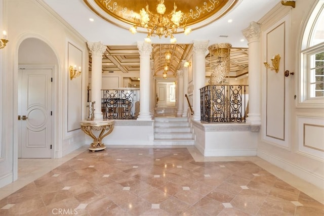 entryway featuring a notable chandelier, decorative columns, coffered ceiling, and crown molding