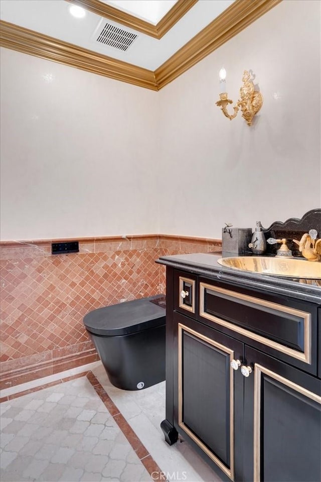 bathroom with a wainscoted wall, visible vents, ornamental molding, toilet, and vanity