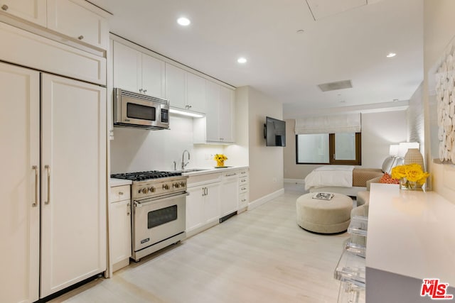 kitchen with sink, appliances with stainless steel finishes, light hardwood / wood-style flooring, and white cabinets