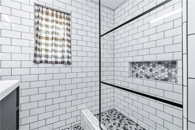 bathroom featuring tiled shower and vanity