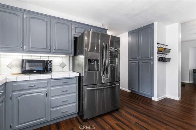 kitchen featuring backsplash, stainless steel fridge, dark hardwood / wood-style flooring, and tile countertops