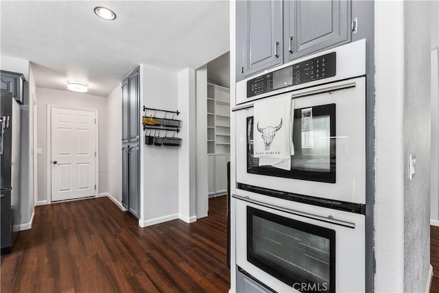 kitchen featuring dark wood-type flooring, gray cabinetry, double wall oven, and fridge