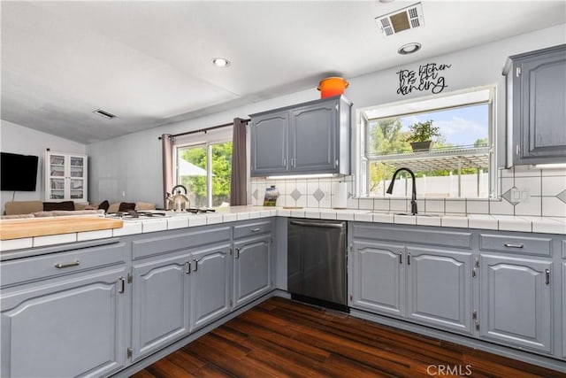 kitchen with gray cabinets, decorative backsplash, stainless steel dishwasher, and sink