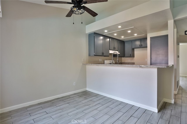 kitchen with gray cabinetry, light stone countertops, ceiling fan, and light hardwood / wood-style flooring