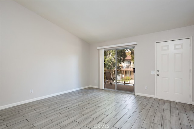 empty room with vaulted ceiling and light hardwood / wood-style flooring