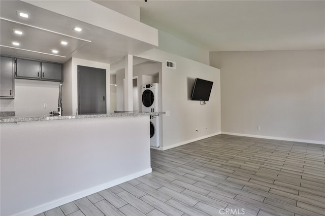 kitchen featuring gray cabinets, light wood-type flooring, and stacked washer / drying machine