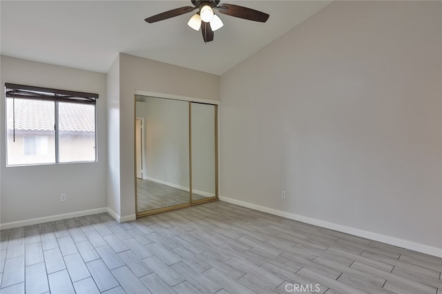 unfurnished bedroom featuring ceiling fan, light wood-type flooring, a closet, and lofted ceiling