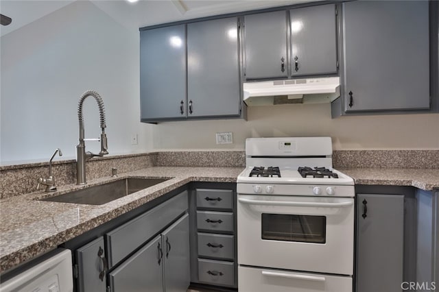 kitchen with gray cabinetry, white appliances, dark stone countertops, and sink