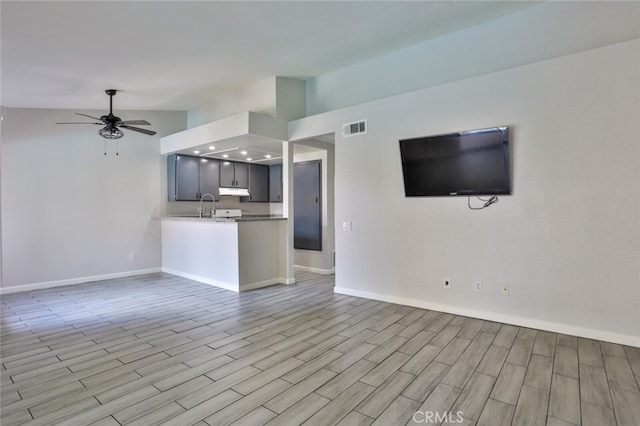 unfurnished living room with light hardwood / wood-style flooring, vaulted ceiling, ceiling fan, and sink