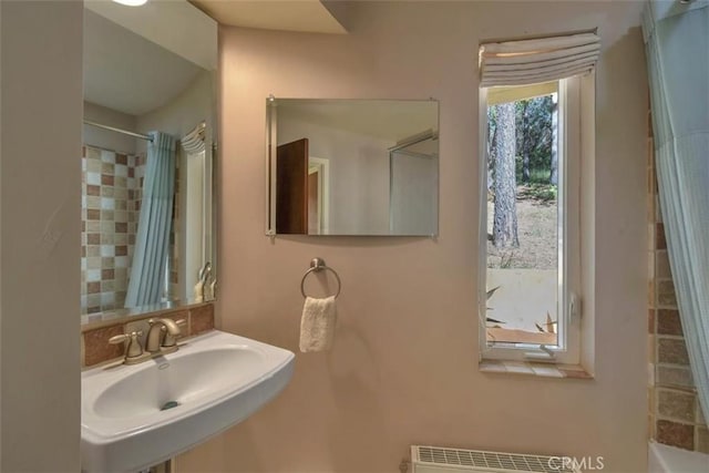 bathroom featuring a shower with shower curtain, a sink, and radiator