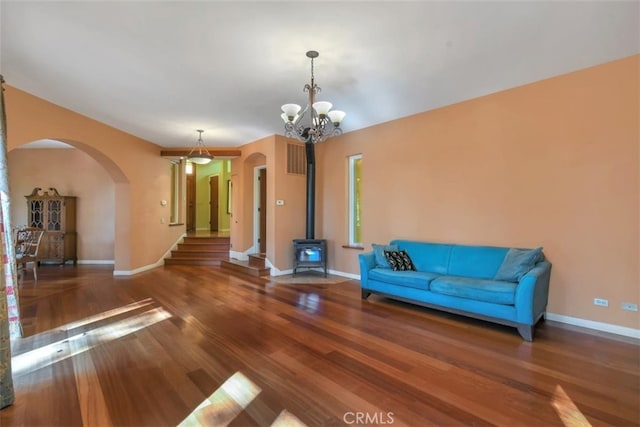 unfurnished living room with a chandelier, hardwood / wood-style floors, and a wood stove