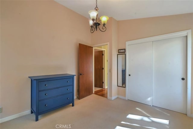 unfurnished bedroom with a closet, light colored carpet, lofted ceiling, and an inviting chandelier