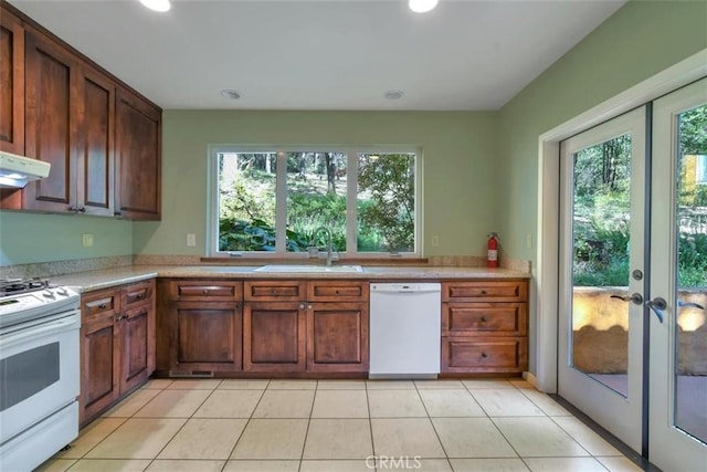 kitchen featuring white appliances, light tile patterned flooring, light countertops, a sink, and french doors