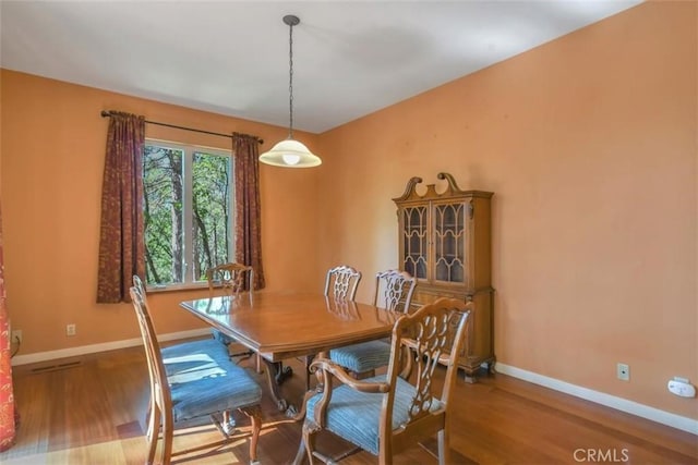 dining space with baseboards and wood finished floors