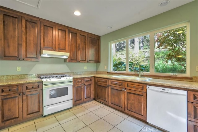 kitchen featuring sink, light tile patterned flooring, and white appliances