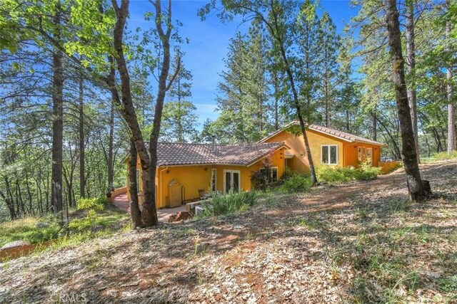 view of side of home featuring stucco siding, french doors, and a tile roof
