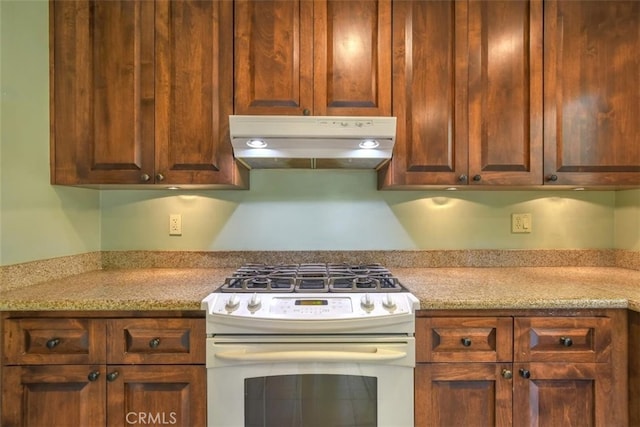 kitchen featuring light stone countertops and white range with gas cooktop