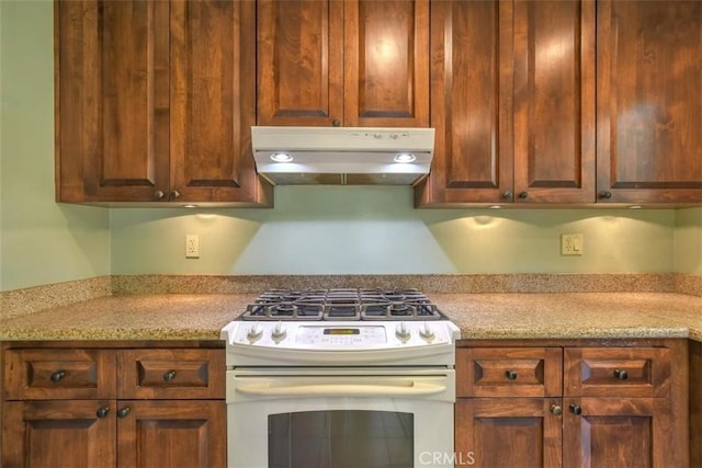 kitchen featuring under cabinet range hood and white gas range oven