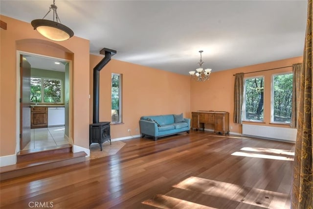 interior space with sink, hardwood / wood-style flooring, an inviting chandelier, radiator heating unit, and a wood stove