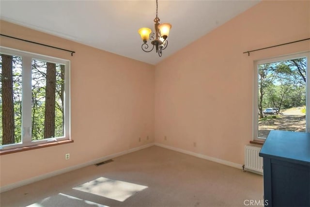 spare room with baseboards, an inviting chandelier, radiator heating unit, visible vents, and light colored carpet