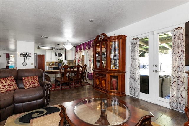 living room featuring a wealth of natural light, a textured ceiling, french doors, and dark hardwood / wood-style floors